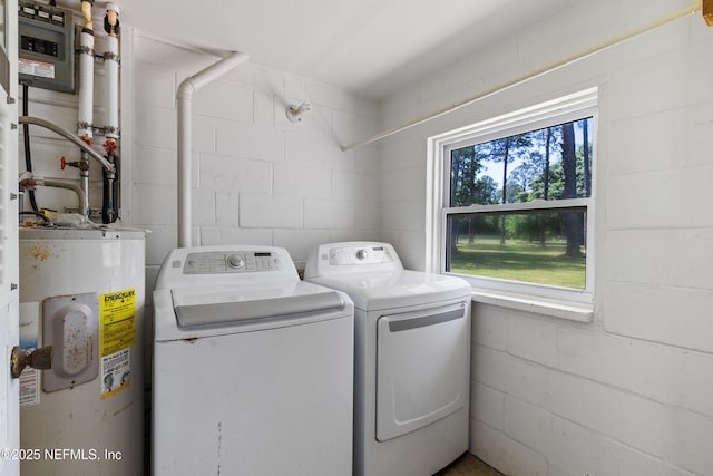 laundry room featuring water heater, concrete block wall, separate washer and dryer, and laundry area