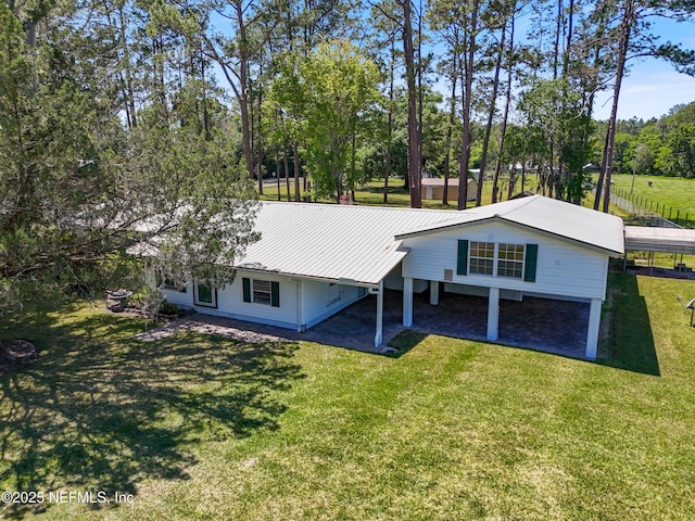 rear view of property with a lawn, a carport, and metal roof