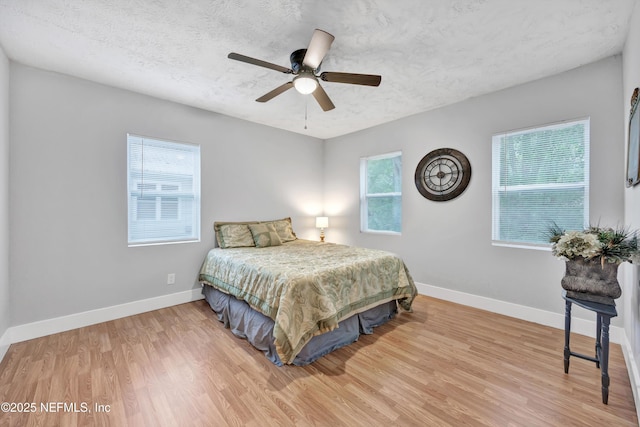 bedroom featuring baseboards, wood finished floors, and multiple windows