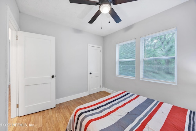 bedroom featuring light wood-style floors, a ceiling fan, and baseboards