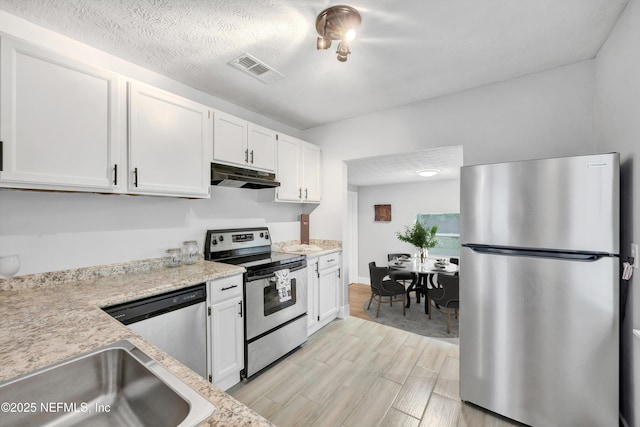 kitchen with visible vents, under cabinet range hood, white cabinets, a sink, and appliances with stainless steel finishes