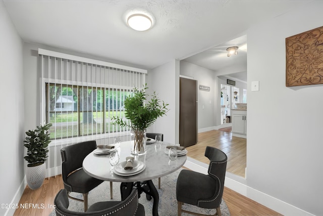 dining space featuring baseboards and light wood-type flooring