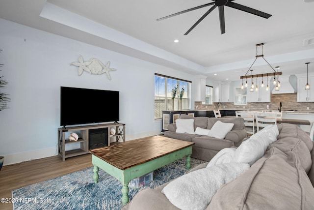 548 Sea Island Dr, Fernandina Beach, FL 32034 - living room featuring light wood-style floors, a tray ceiling, baseboards, ceiling fan, and recessed lighting