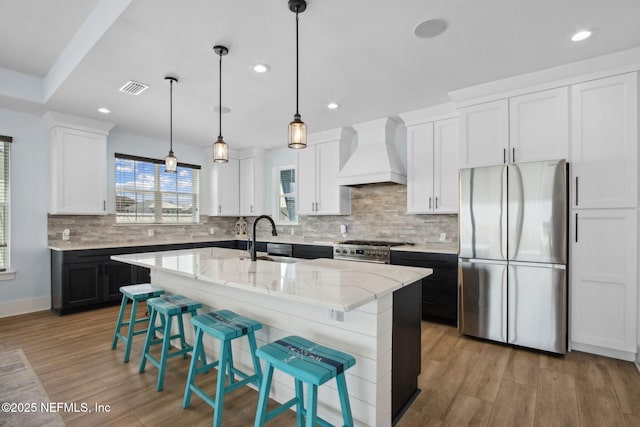 548 Sea Island Dr, Fernandina Beach, FL 32034 - kitchen featuring appliances with stainless steel finishes, custom range hood, recessed lighting, light stone counters, and a kitchen breakfast bar