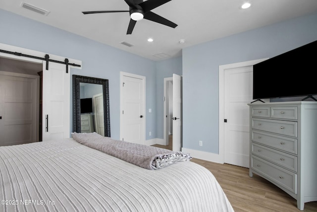 548 Sea Island Dr, Fernandina Beach, FL 32034 - bedroom featuring light wood-type flooring, a barn door, recessed lighting, baseboards, and ceiling fan
