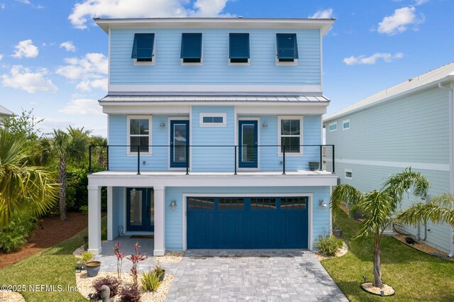 548 Sea Island Dr, Fernandina Beach, FL 32034 - coastal inspired home featuring a balcony, a front lawn, decorative driveway, an attached garage, and metal roof