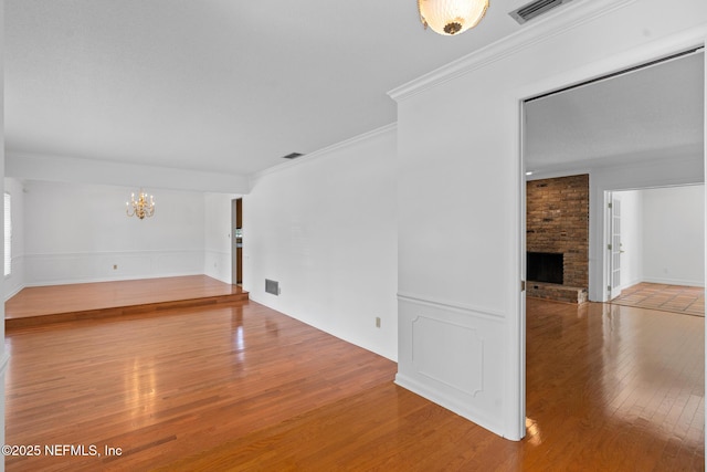 1228 Old Mill Rd, Orlando, FL 32806 - unfurnished room featuring visible vents, ornamental molding, hardwood / wood-style floors, a fireplace, and a chandelier