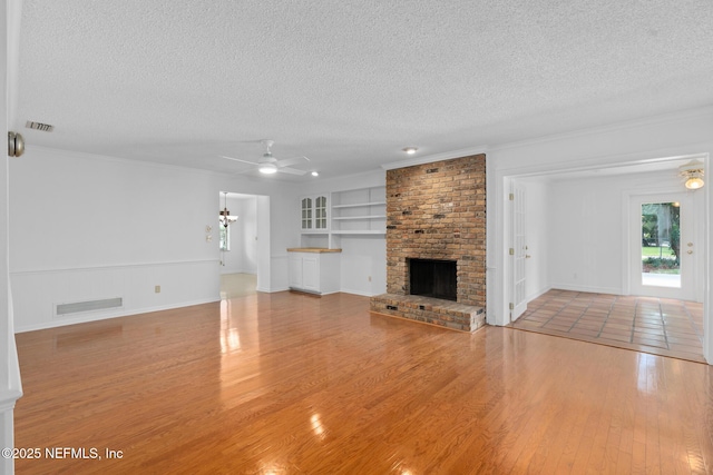 1228 Old Mill Rd, Orlando, FL 32806 - unfurnished living room featuring a ceiling fan, a textured ceiling, visible vents, built in features, and wood finished floors
