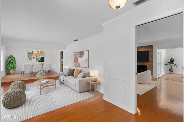 1228 Old Mill Rd, Orlando, FL 32806 - living area featuring crown molding, a notable chandelier, light wood-style floors, a brick fireplace, and visible vents