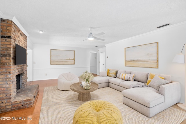 1228 Old Mill Rd, Orlando, FL 32806 - living area featuring visible vents, wood finished floors, a fireplace, ceiling fan, and a textured ceiling