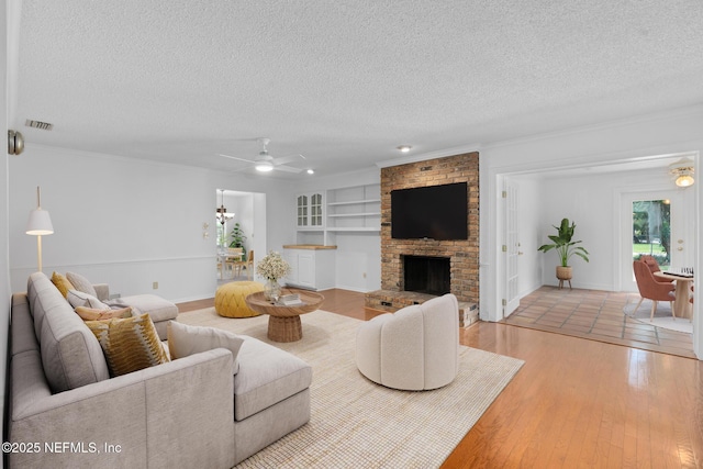 1228 Old Mill Rd, Orlando, FL 32806 - living area with wood-type flooring, a fireplace, a textured ceiling, built in shelves, and a ceiling fan