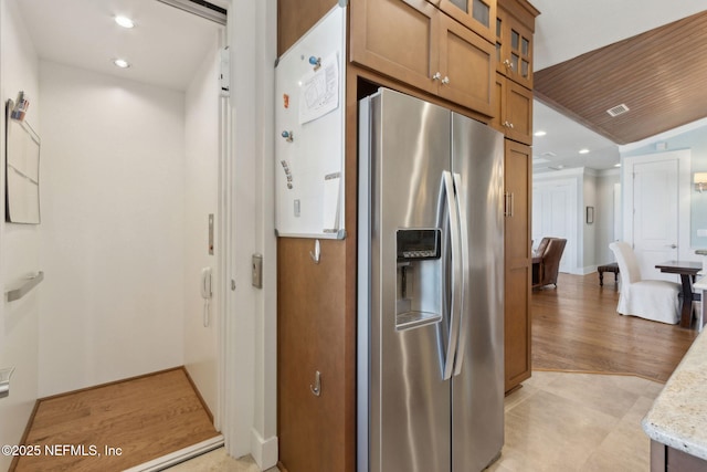 111 Cherry St, Neptune Beach, FL 32266 - kitchen with brown cabinets, glass insert cabinets, stainless steel fridge, visible vents, and recessed lighting