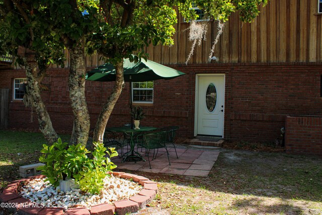 view of exterior entry with brick siding and a patio area
