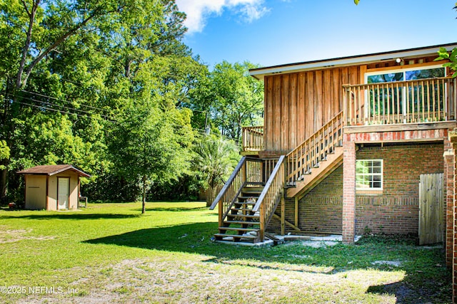 view of yard with a wooden deck, a storage unit, an outbuilding, and stairway