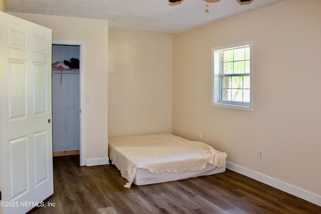 bedroom with baseboards, dark wood-style floors, and a closet