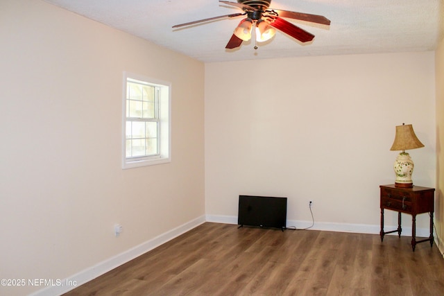 empty room with wood finished floors, a ceiling fan, and baseboards