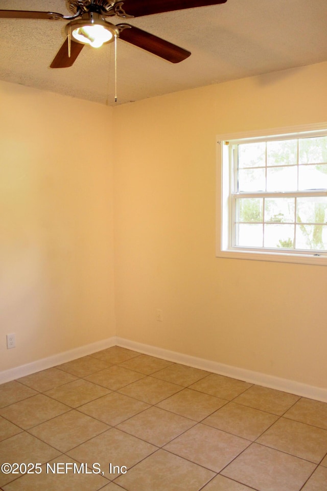 unfurnished room featuring a ceiling fan, baseboards, and light tile patterned floors