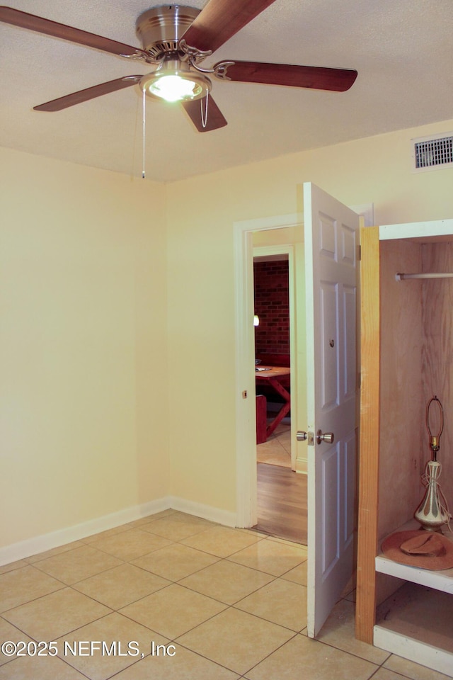 interior space with light tile patterned floors, baseboards, visible vents, and ceiling fan
