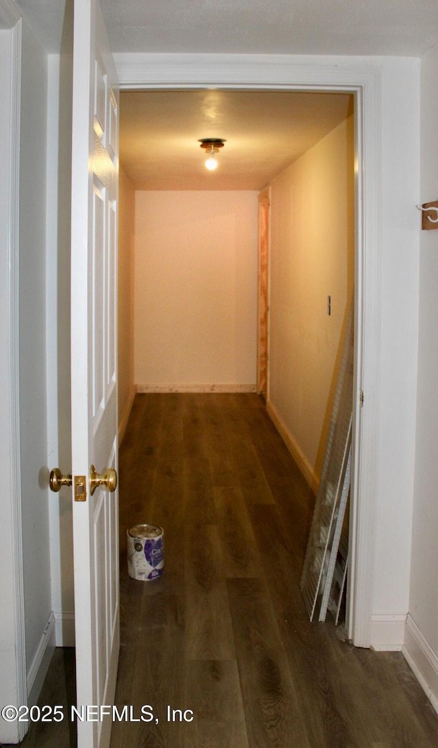 corridor with baseboards and wood finished floors
