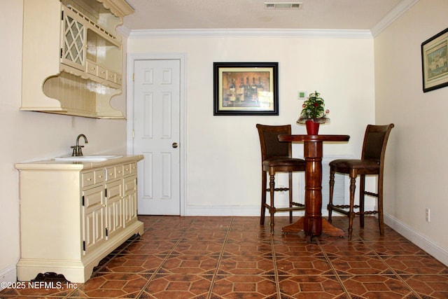 interior space with stone finish flooring, baseboards, crown molding, and a sink