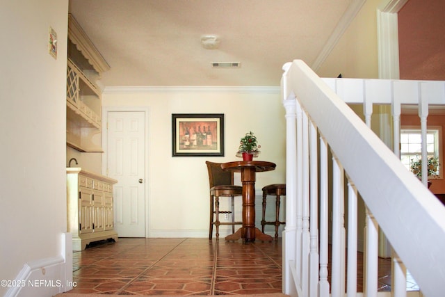 interior space featuring baseboards, ornamental molding, and visible vents