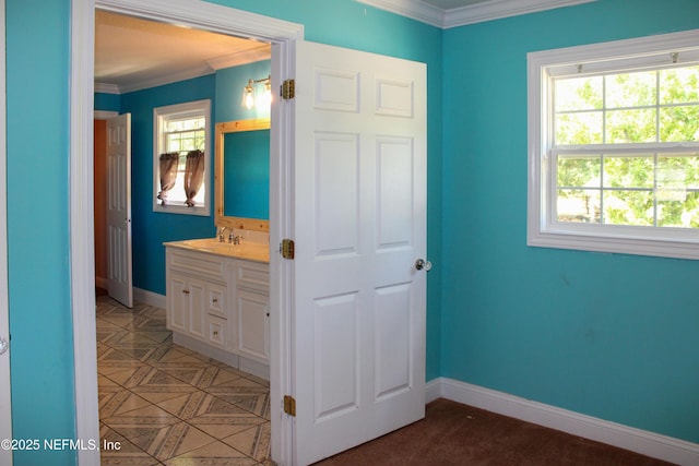bathroom with baseboards, crown molding, and vanity