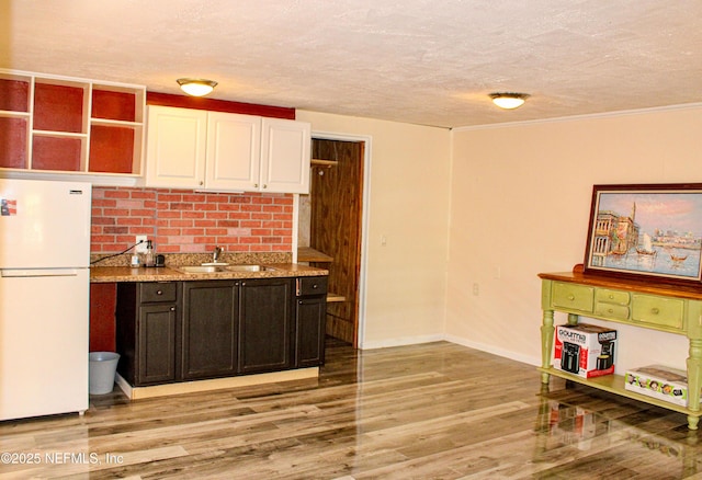 kitchen featuring white cabinets, light wood-style floors, a sink, and freestanding refrigerator