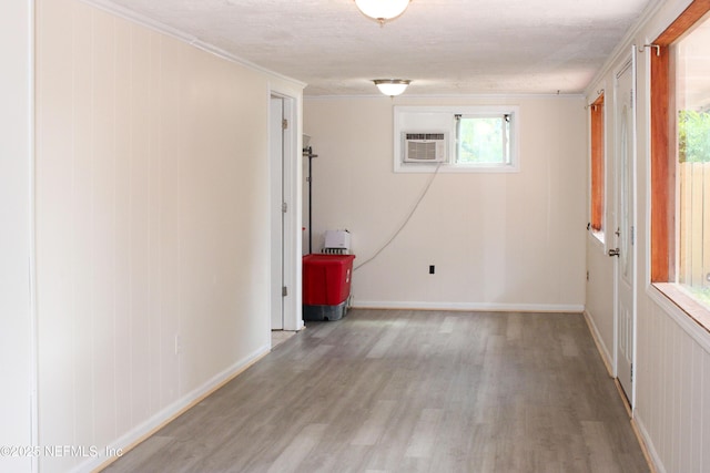 spare room with baseboards, light wood-style floors, and a wall unit AC