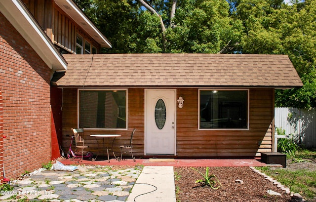 entrance to property with roof with shingles and fence