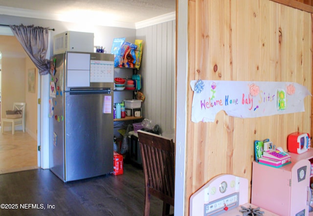 interior space with wood walls, crown molding, wood finished floors, and freestanding refrigerator