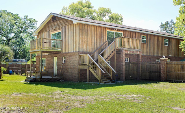 rear view of house with fence, a lawn, a wooden deck, and stairway