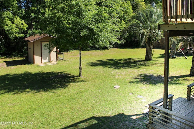 view of yard featuring a wooden deck, a storage unit, and an outbuilding
