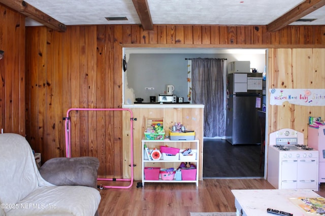 interior space with wooden walls, wood finished floors, beam ceiling, and visible vents