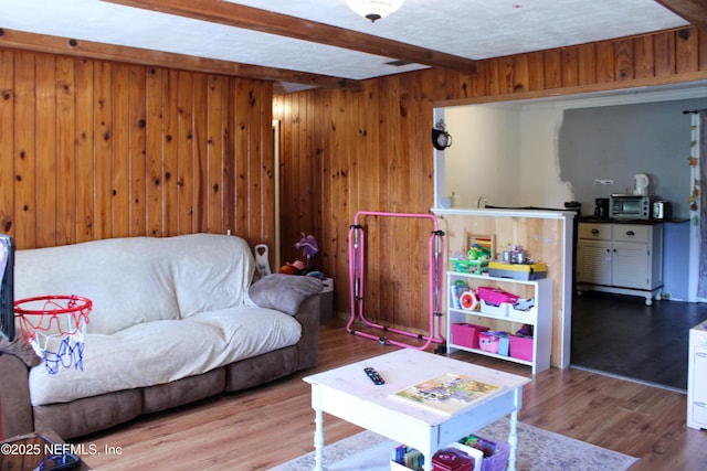 living room featuring beamed ceiling, wooden walls, and wood finished floors