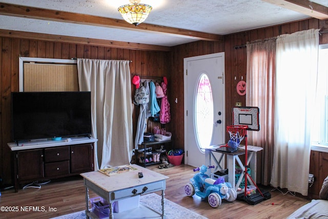 interior space featuring wood walls, wood finished floors, and beam ceiling
