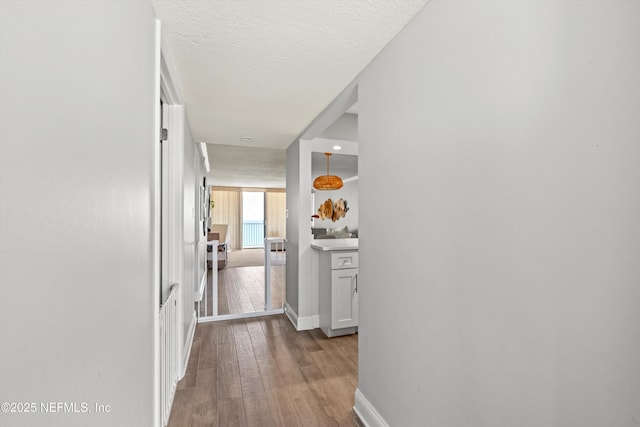 1301 1st St S Unit 1507, Jacksonville Beach, FL 32250 - hallway featuring baseboards, a textured ceiling, and wood-type flooring
