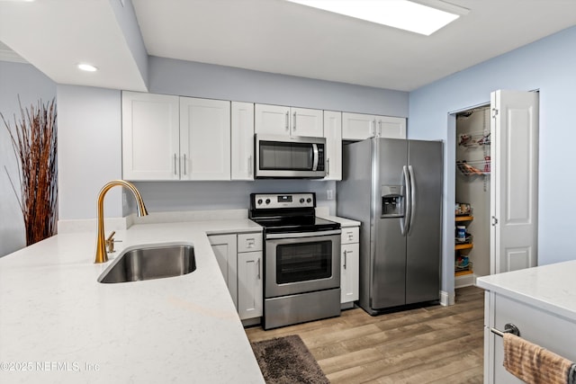 1301 1st St S Unit 1507, Jacksonville Beach, FL 32250 - kitchen featuring white cabinets, light wood-style flooring, stainless steel appliances, and a sink