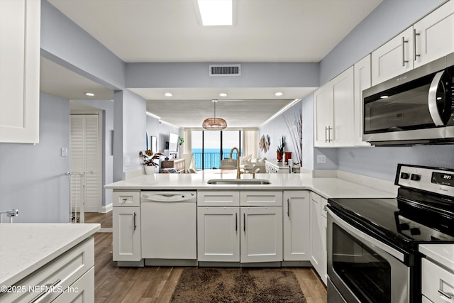 1301 1st St S Unit 1507, Jacksonville Beach, FL 32250 - kitchen with stainless steel appliances, a sink, dark wood-style flooring, visible vents, and white cabinetry