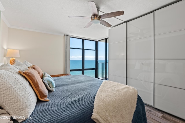 1301 1st St S Unit 1507, Jacksonville Beach, FL 32250 - bedroom with wood finished floors, a textured ceiling, a water view, ceiling fan, and a wall of windows