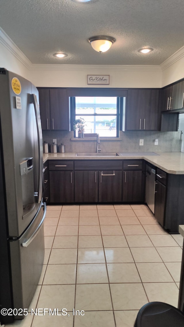 kitchen with a textured ceiling, crown molding, a sink, light countertops, and stainless steel appliances