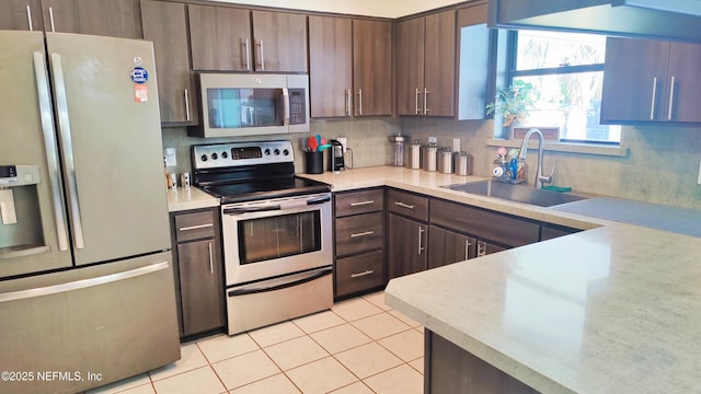 kitchen featuring appliances with stainless steel finishes, a sink, light countertops, decorative backsplash, and light tile patterned floors