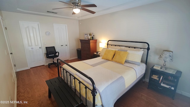 bedroom with visible vents, a ceiling fan, baseboards, and wood finished floors