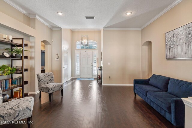 entrance foyer featuring wood finished floors, visible vents, arched walkways, and a notable chandelier
