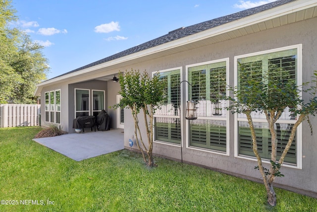 back of house with stucco siding, a patio area, a ceiling fan, and a lawn