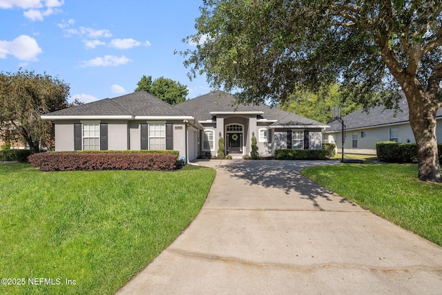 view of front facade with stucco siding, driveway, a garage, and a front yard