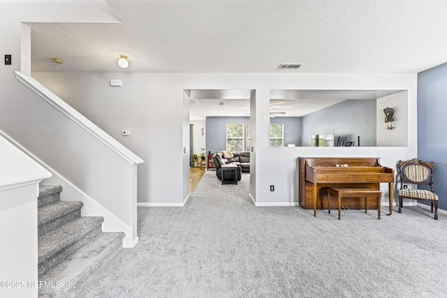 sitting room featuring stairway, a textured ceiling, carpet, baseboards, and visible vents