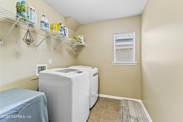 washroom featuring baseboards, tile patterned floors, washer and clothes dryer, and laundry area