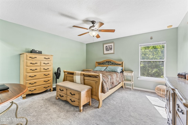 bedroom with ceiling fan, baseboards, a textured ceiling, and light colored carpet