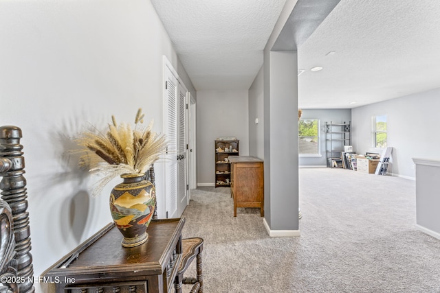 corridor with baseboards, carpet flooring, and a textured ceiling