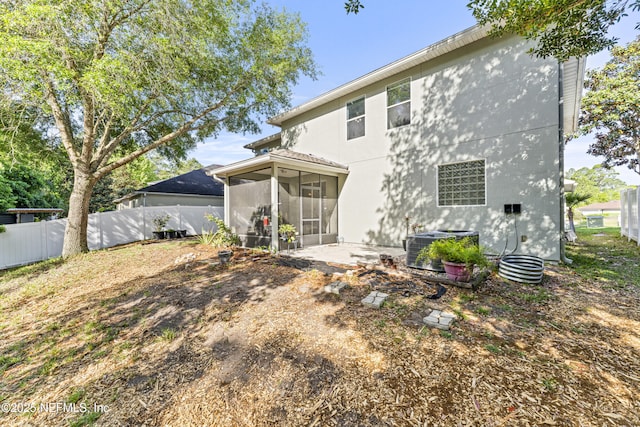 rear view of property with fence, a sunroom, cooling unit, and stucco siding